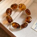 Amber acrylic irregular oval bead bracelet with gold spacers in a beige jewelry box - Brown