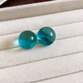 Vista de pendientes redondos de resina verde azulado translúcido en bandeja de joyería de crema - Azul