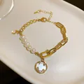 Detail eines Süßwasserperlen-Armbands im französischen Stil mit goldenen Anhängern. - Gold (Süßwasserperle)