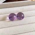 Vista macro de pendientes redondos de resina morada en una bandeja de terciopelo beige - Púrpura