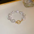 Gros plan d'un élégant bracelet en perles baroques blanches avec fermoir OT doré - Style Perle Irrégulière avec Fermoir en T (4#) / Blanc Crème (Fermoir en T Doré)