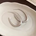 Vista dettagliata di orecchini a cerchio ovali in argento su un piatto ceramico - Argento
