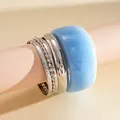 Close-up detail of a five-piece minimalist bracelet set featuring silver metal and blue resin - Stackable Bangle Collection / Silver & Blue