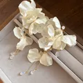 Dettagliata vista ravvicinata di eleganti orecchini a fiore in chiffon crema con perle - Perno in argento-Bianco / Bianco