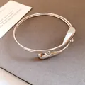 Close-up macro view of elegant silver double-layer open bangle with teardrop ends - Silver