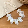 Détail d'un collier en perles acryliques irrégulières avec d'élégantes vagues blanches. - Collier / Transparent