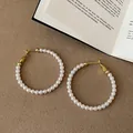 Eleganti orecchini a cerchio di perle con accenti dorati su superficie testurizzata. - Stile a Cerchio con Perline / Oro Bianco