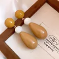 Detailed view of vintage resin water-drop earrings in warm amber and white tones. - Brown