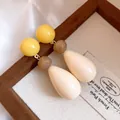 Close-up detail of retro resin waterdrop earrings featuring yellow and cream bead accents - White