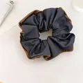 Macro detail view of a stylish blue denim scrunchie with elegant brown fabric trim - Hair Tie / Blue