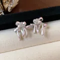 Gros plan de boucles d'oreilles nœud en argent avec zircons sur présentoir en velours - Rose / Argent