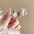 Detailaufnahme von silbernen Hohlblumen-Ohrsteckern mit einer edlen Perlenmitte - Silbernadel / Silber-Weiß