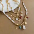 Detail of layered beach necklace with baroque pearls, gold starfish, and shell charms. - Necklace Set / Gold White