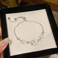 Primer plano de una elegante pulsera de margaritas de plata con esmalte blanco y circonitas - Blanco/Plata