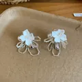 Close-up detail of elegant white shell flower earrings with pearls and clear beads. - Flower Style / White