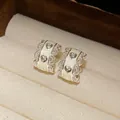 Primer plano de elegantes pendientes de aro en C con bordes de encaje y motivos corazón - Estilo de esmalte de corazón / Plateado