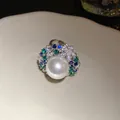 Elegant vintage pearl ring with blue and green zircons on a white ceramic plate - Ring / Silver-Green