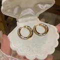 Macro view of luxury 18K gold plated hoop earrings with black and white zircon in shell box - Gold