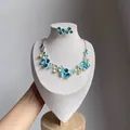 Primo piano di un elegante set di collana e orecchini a lobo in smalto floreale blu e verde - Set di Fiori Verdi / Oro-Verde