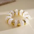Detailed macro view of white marbled acrylic and gold geometric beaded bracelet. - Clear