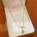 Gros plan d'un collier plaqué or 18k avec pendentif turquoise en goutte dans un écrin vert - Collier-Or-Bleu (Plaqué Or Véritable)