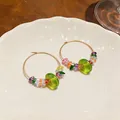 Detailed view of colorful resin beaded gold hoop earrings on white ceramic plate - Round (HE31813) / Gold-Green