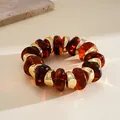 Detailed macro view of amber acrylic beads and golden spacers on a textured surface - Brown