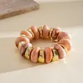 Close-up detail of peach marble acrylic and gold irregular geometric beaded elastic bracelet - Pink