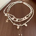Vue détaillée de la chaîne de taille en perles avec pendentifs coquillages et étoile de mer - Style Conque Coquillage Étoile de Mer (HN11720) / Or-Blanc