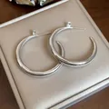 Close-up of silver-plated hoop earrings with sparkling zircon studs on a luxury box. - Round Style / Silver