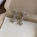 Close-up detail of elegant silver-toned hollow flower tiered clip-on earrings for women - 镂空花朵耳夹(HE32212) / Silver