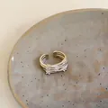 Close-up of a multi-layered silver open ring with zircon stones on a ceramic plate. - 3# Ring-Silver