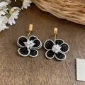 Dettaglio ravvicinato di orecchini eleganti a fiore in chiffon nero con perle e oro - Gancio per Orecchio Dorato (HE32493) / Nero