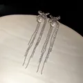 Elegant detail of silver bowknot tassel earrings featuring shimmering pearls and rhinestones - Silver