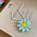 Detailed view of light blue flower pendant on beaded necklace over a book - Blue