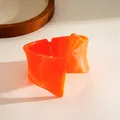 Detail shot of a bright orange resin bangle with a unique twisted geometric design - Orange