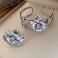 Detailaufnahme eines silberfarbenen Blumenschmuck-Sets mit Perlen für einen eleganten Look - Armband Und Ring Set / Silber