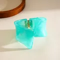 Irregular twisted geometric bangle made of marbled turquoise resin with a hinged opening. - Cyan