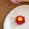 Close-up of a vibrant daisy beaded necklace on a white ceramic plate - Red