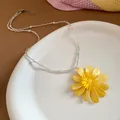 Macro detail view of a vibrant yellow daisy beaded necklace on a white ceramic plate - Yellow