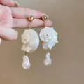 Detailed view of handmade shell conch dangle earrings featuring elegant baroque pearl drops - White
