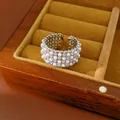 Macro detail of a silver-toned open ring featuring layers of white pearls and zirconia stones - Silver-White
