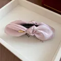 Gros plan d'une pince à cheveux banane en satin rose élégante avec détail doré - Style Nœud / Rose