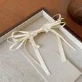 Dettaglio ravvicinato di un'elegante clip per capelli a fiocco crema con fiori di perla - Clip a Becco d'Anatra (Pezzo Singolo) / Bianco