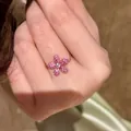 Elegant vintage pink flower chain ring featuring pavé crystals shown on a finger - Ruby Red