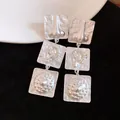 Detail of vintage matte silver square drop earrings with unique embossed anatomical motifs. - Silver
