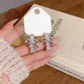 Detalle de cerca de elegantes pendientes de lazo plateados con circonitas. - Plateado