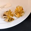Macro view of elegant gold-plated flower petal stud earrings featuring a high-gloss finish. - Gold