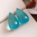 Vista dettagliata di eleganti orecchini a goccia in resina ciano su sfondo color crema. - Blu-Grande