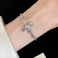 Close-up detail of a silver-tone bracelet featuring a heart-shaped floral cross with colorful gems. - Silver Metal Chain Bracelet / Silver